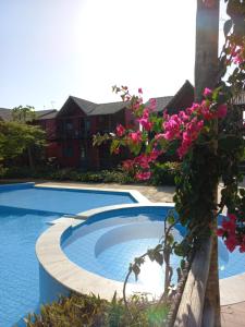 una piscina con flores rosas junto a una casa en Chaleville Coqueiro 1001, en Luís Correia