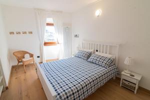 ein Schlafzimmer mit einem Bett mit einer karierten Decke und einem Fenster in der Unterkunft cottage lavanda e rosmarino in Lavis