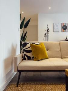Luxe Pad London with Free Parking في برينتفورد: أريكة مع وسائد صفراء في غرفة المعيشة
