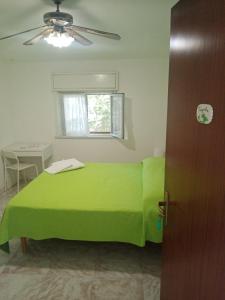 a green bed in a room with a window at Casa Siciliana Altarbiah in Trabia