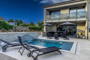 a house with a swimming pool with chairs and an umbrella at Villa More in Krk