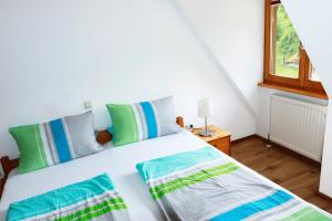 a bedroom with a white bed with green and blue pillows at Mayer Burghöfe in Owingen