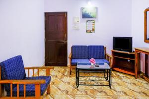 a living room with two chairs and a table and a tv at OYO Mahamaya Holiday Inn Near Calangute Beach in Calangute