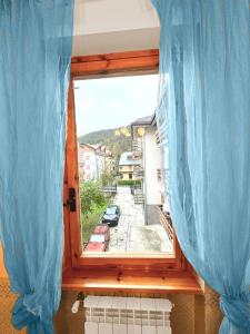 a window with blue curtains and a view of a street at The Flowers - Casa Calicanto in Roccaraso