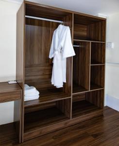 a wooden wardrobe with a white robe hanging on it at Covent Garden Hotel in Ho Chi Minh City