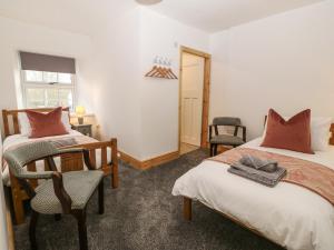 a bedroom with two beds and a desk and a chair at Y Cigydd in Derwen