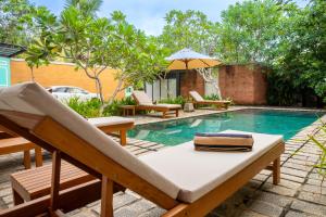 a swimming pool with chairs and a table next to a pool at Villa V Kalutara in Wadduwa