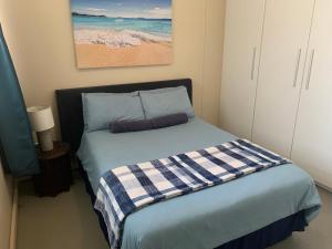een slaapkamer met een bed met een geruite deken bij The Waves, 302 Quayside Point Waterfront in Durban +13 foto's