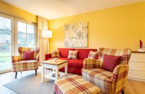 a living room with a red couch and two chairs at Hotel Landhaus Ellerbrock in Sankt Peter-Ording