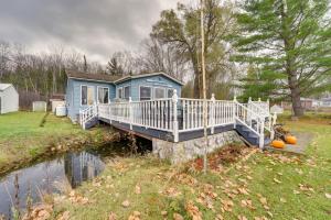 ein blaues Haus auf einer Brücke über einen Fluss in der Unterkunft All-Season Lakefront Reed City Home on 2 Acres! in Reed City