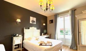 a bedroom with a white bed and a chandelier at La Villa Les Mots Passants in Cabourg