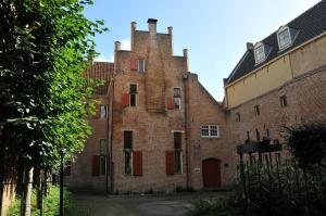 un viejo edificio de ladrillo con una torre encima en Stadslogement Goudsteeg 19B en Zwolle