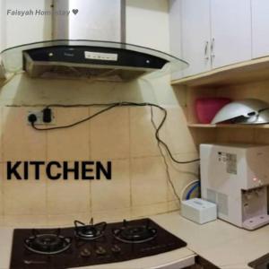 a kitchen with a stove and a microwave at FAISYAH HOMESTAY in Lahad Datu