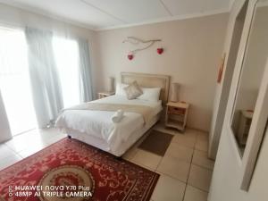 um quarto com uma cama branca e um tapete vermelho em Akkerdam Bed and Breakfast em Calvinia