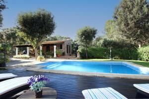una piscina en un patio con bancos y flores en Villa Pedro Monjo, en Pollensa