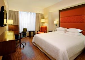 a hotel room with a large bed and a desk at Four Points by Sheraton Ahmedabad in Ahmedabad