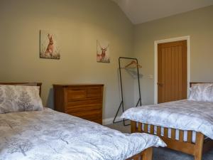 a bedroom with two beds and a dresser at Striding Edge Cottage in Glenridding