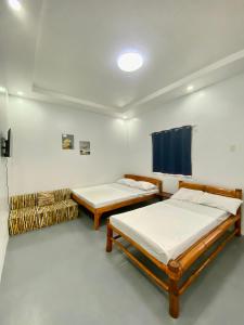 a room with two beds and a tv in it at La Casa Blanca Binoclutan in Botolan