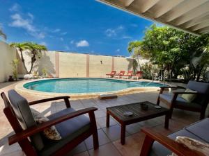 a swimming pool with chairs and a table next to it at Beachside Villa at Boca Catalina in Palm-Eagle Beach