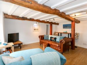 a living room with a couch and a tv at Leveret Cottage in Docking