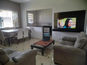 ein Wohnzimmer mit einem Fernseher an der Wand in der Unterkunft Peruíbe - Oasis - Casa espaçosa, lugar tranquilo in Peruíbe