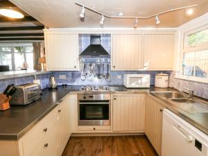 una cucina con mobili bianchi e un forno a piano cottura di The Cottage a Pwllheli