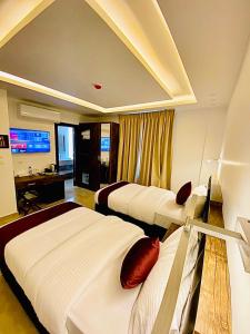 ein Hotelzimmer mit 3 Betten und einem Schreibtisch in der Unterkunft Petra Bermudez Hotel in Wadi Musa