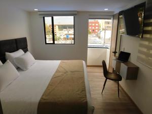 a bedroom with a bed and a chair and a window at HOTEL MX BOGOTA in Bogotá
