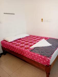 a bed in a room with a red bedspread on it at Yasin Guest house in Puducherry