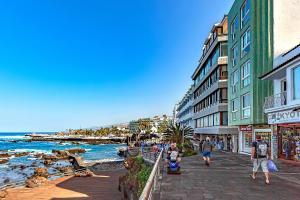 a group of people walking down a sidewalk next to the ocean at Lovely apartment Lavaggi sea view in Puerto de la Cruz