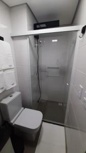 une salle de bain avec toilettes et douche en verre dans l'établissement Studio 110 Maravilhoso Vista Mar Piscina Aquecida, à Matinhos