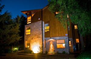 un bâtiment avec des lumières devant lui la nuit dans l'établissement Manke Apart & Suites, à San Martín de los Andes