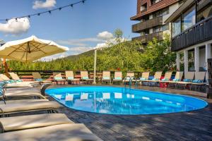 uma piscina com espreguiçadeiras e um guarda-sol em Alpin ApartHotel 2302 em Poiana Brasov