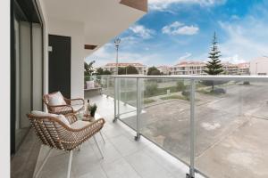 a balcony with two chairs and a view of a courtyard at Consolação Wave Beach House in Atouguia da Baleia
