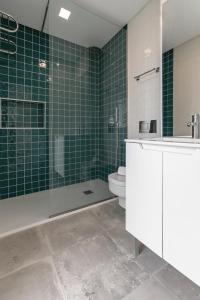 a bathroom with a shower and a toilet and green tiles at Consolação Wave Beach House in Atouguia da Baleia