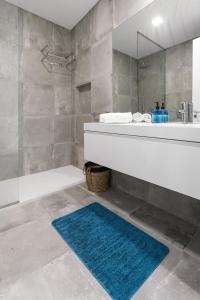 a bathroom with a white sink and a blue rug at Consolação Wave Beach House in Atouguia da Baleia