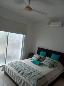 - une chambre avec un lit doté d'oreillers bleus et d'une fenêtre dans l'établissement Conjunto Santa Ana, à Flandes