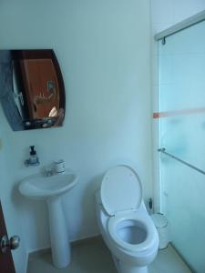La salle de bains blanche est pourvue de toilettes et d'un lavabo. dans l'établissement Conjunto Santa Ana, à Flandes
