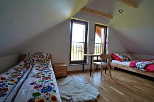 a bedroom with two beds and a table and windows at Kuźnia Nowica in Uście Gorlickie