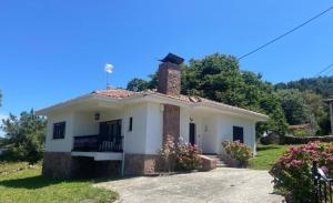 una pequeña casa blanca con chimenea en Villa May en Riegu Vidiago Llanes, en Vidiago