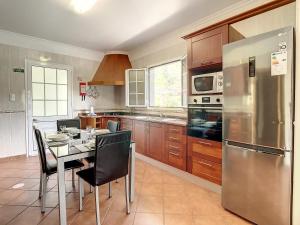 Una cocina con una mesa y un refrigerador de acero inoxidable. en Mountain View Villa by Atlantic Holiday, en São Vicente