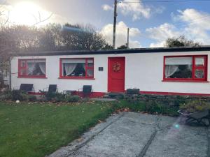 a white house with a red door and windows at The Potters Cottage in Clifden