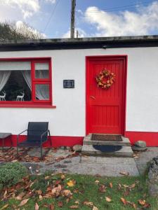 a red door on a white house with a window at The Potters Cottage in Clifden