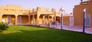 un bâtiment avec une pelouse verte devant lui dans l'établissement شاليه غرناطة, à Al Khabrāʼ