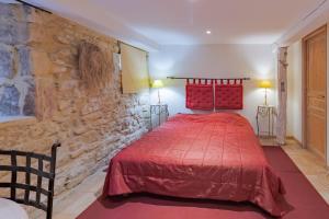 sypialnia z czerwonym łóżkiem i kamienną ścianą w obiekcie Gite Monfort w mieście Sainte-Mondane