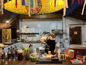 a man in a kitchen preparing food in a kitchen at Lagarto Na Banana Hostel in Pipa