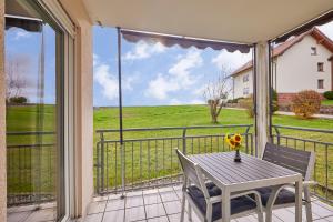 a table and chairs on a balcony with a view of a field at NEW-Emma - Glashofen Walldürn in Walldürn