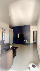 sala de estar con pared azul y TV de pantalla plana en MESSÉ Home Stay, en General Santos