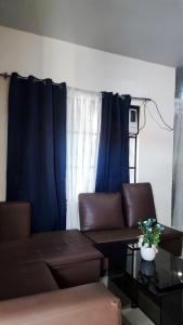 salon z brązową kanapą i niebieskimi zasłonami w obiekcie MESSÉ Home Stay w mieście General Santos