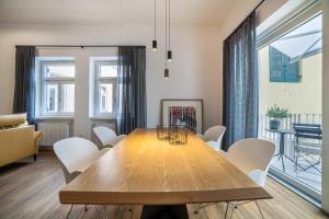une salle à manger avec une table en bois et des chaises blanches dans l'établissement Amort Suites, à Merano